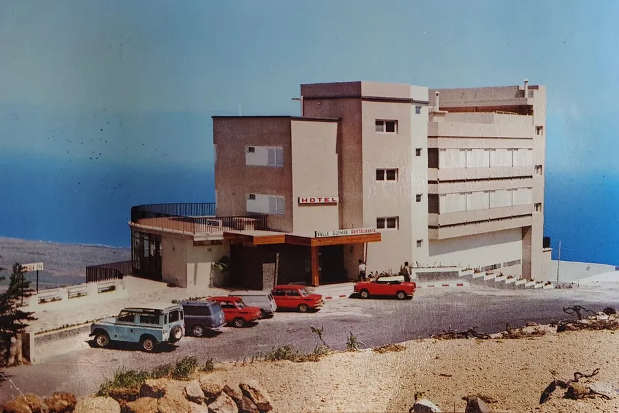 Historic photo of the hotel in the sixties, with classic cars out front and the sea behind